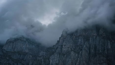 Storm-clouds-roll-up-along-Klausen-pass-as-sunlight-dances-on-granite-cliffs-of-Urnerboden-Switzerland