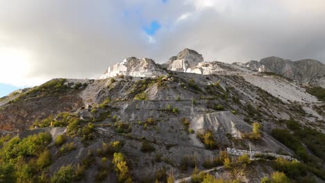 Limestone-quarry-on-Apuan-Alps-with-autumn-trees-under-cloudy-skies,-Tuscany,-Italy