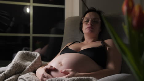 Mujer-Embarazada-Descansando-En-El-Sofá-En-Casa,-Noche,-Comodidad-Con-Una-Manta-Suave