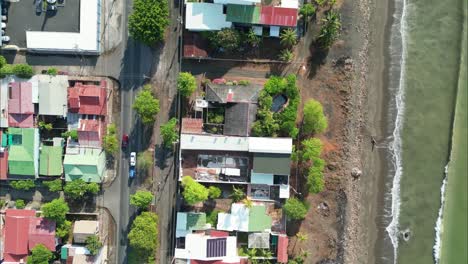Flying-over-the-coast-of-Costa-Rica-with-houses-and-crashing-waves