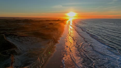The-beach-is-washed-by-sea-waves,-high-dunes-have-formed,-the-summer-house-standing-on-the-dunes-is-surrounded-by-a-mystical-mist,-and-the-sun-is-setting-on-a-winter-evening