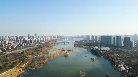 Panoramic-aerial-dolly-above-Benghe-River-and-Linyi-downtown-city-connected-by-a-bridge