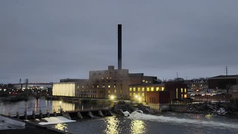 Early-morning-shot-of-factory-with-smoke-stack-and-dam-across-the-river-in-the-morning