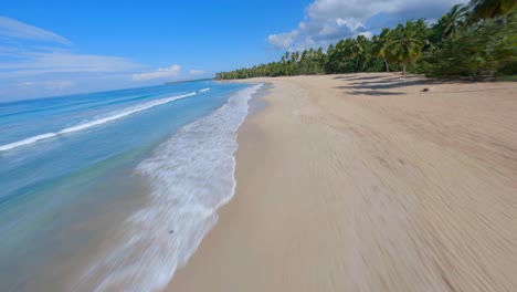 FPV-aerial-flies-low-along-turquoise-blue-waves-crashing-on-golden-sandy-cove-of-Coson-Beach-Samana-Dominican-Republic