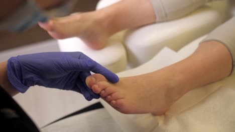Der-Professionelle-Fußpfleger-Reinigt-Die-Nagelhaut-Des-Weiblichen-Fußzehennagels-Mit-Handschuhen-Und-Werkzeug