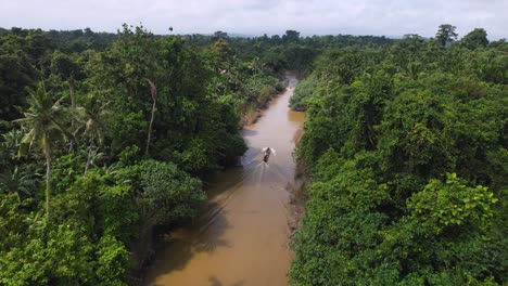 An-ariel-4K-drone-view-of-a-longtail-boat-floating-down-a-river-in-the-jungle