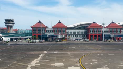 Außenansicht-Des-Terminalgebäudes-Und-Der-Asphaltierten-Landebahn-Mit-Transportfahrzeugen,-Die-Am-Internationalen-Flughafen-Ngurah-Rai-Fahren