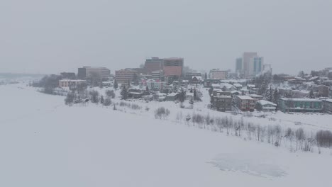Anchorage-Alaska,-pull-back-reveal-drone-shot,-cloudy-snowy-weather