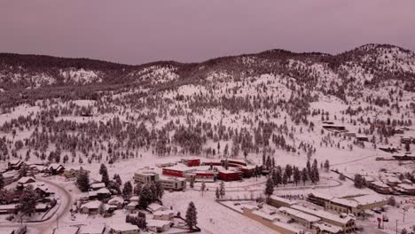 A-circular-building-sits-next-to-a-dense-forest-and-snow-covered-mountains-in-the-city-of-Merritt,-British-Columbia