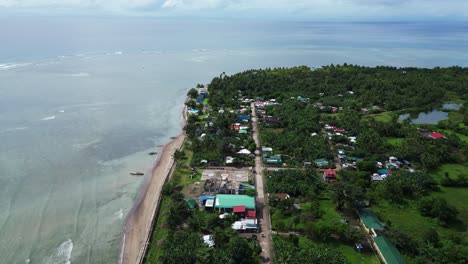 Aerial-drone-view-of-rural,-coastal-fishing-village-on-tropical-island-with-lush-jungles-and-idyllic-sea-coast