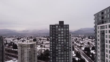 Die-Kamera-Hebt-Sich-Und-Gibt-Den-Blick-Auf-Schneebedeckte-Berge-Und-Eine-Stadtlandschaft-Frei