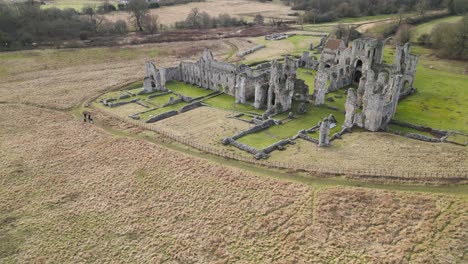 Castle-acre-priory-ruins-in-southern-park-norwich,-historic-architecture-surrounded-by-fields,-aerial-view