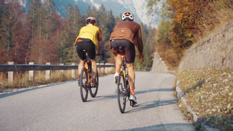 two-male-bicycle-riders-going-up-to-the-mountain-in-full-riding-gear,-and-helmets-in-the-Slovenian-Alps