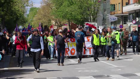 Activists-marching-at-environmental-protest-in-Stockholm,-broad-daylight,-banners-raised