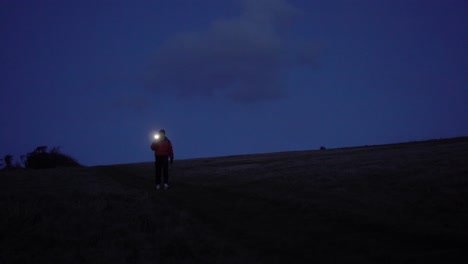 Einsamer-Mann,-Der-Mit-Einer-Handy-Taschenlampe-Durch-Die-Landschaft-Geht