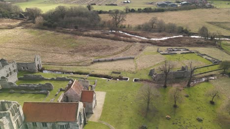 Castle-Acre-Priory-Ruinen-In-Norfolk-Mit-Umliegender-Graslandschaft,-Bei-Tageslicht-Aufgenommen,-Luftaufnahme
