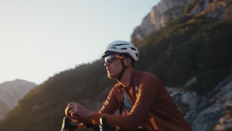 Männlicher-Radfahrer-Ruht-Sich-Während-Des-Sonnenuntergangs-In-Voller-Reitausrüstung-Und-Helm-Auf-Seinem-Fahrrad-Aus