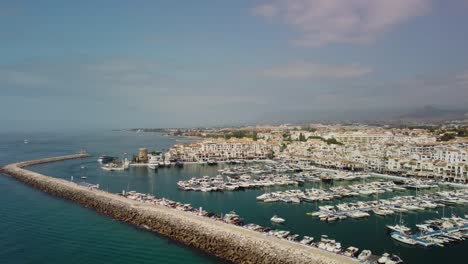 Puerto-banus-marina-in-marbella-with-boats-and-coastline,-sunny-day,-aerial-view