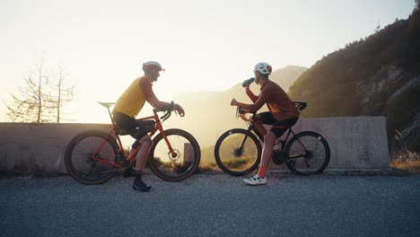 two-bicycle-riders-taking-a-rest-in-the-mountains-at-sunset
