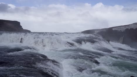 Majestic-Gullfoss-waterfall-in-Iceland-with-misty-spray,-cloudy-skies