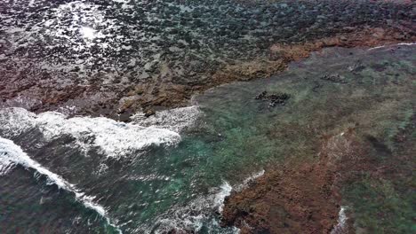 Corralejo's-rocky-coastline-with-clear-turquoise-waters,-fuerteventura,-aerial-view