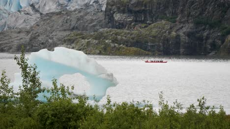 Tourists-kayaking-on-Mendenhall-Lake,-iceberg-floating-on-the-lake,-Alaska