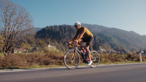 Ciclista-De-Carretera-Masculino-En-Bicicleta-Por-Las-Montañas-Eslovenas-Con-Toda-La-Marcha,-Incluido-Casco-Y-Capa-Inferior