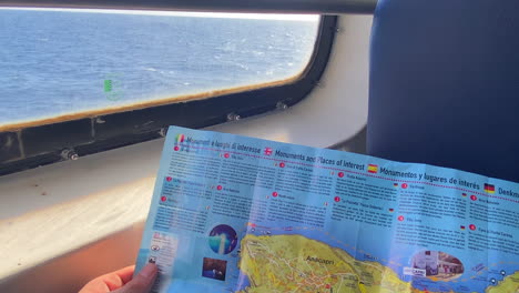 Passenger-holding-a-map-of-Capri-island-inside-the-traveling-ferry