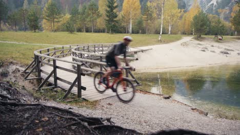 a-man-riding-his-bike-in-the-mountains-and-crossing-a-wooden-bridge
