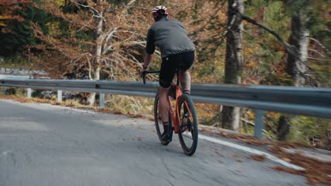 Ein-Männlicher-Radfahrer-Rollt-Mit-Seinem-Rennrad-Mit-Helm-Und-Voller-Ausrüstung-Den-Hügel-Hinunter