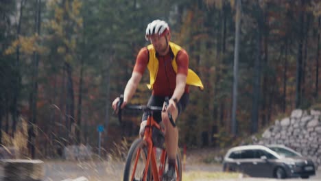 A-male-cyclist-riding-his-road-gravel-bike-up-to-mountain-at-a-high-pace-wearing-full-gear-with-a-helmet