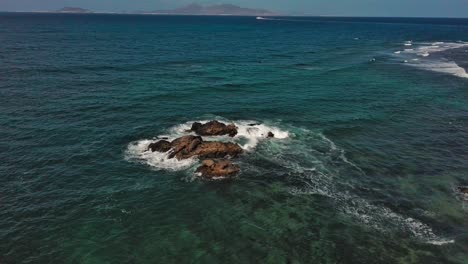 Waves-crashing-on-rocks-off-corralejo-coast,-canary-islands,-clear-day,-aerial-view