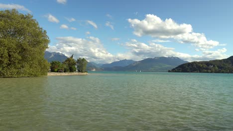 Panoramic-view-of-lake-annecy-and-its-mountains-with-a-blue-sky-and-some-clouds