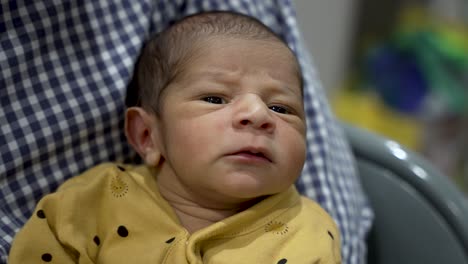 1-Week-Old-Baby-Boy-Being-Held-In-Fathers-Arms-As-He-Looks-Around-Expressively