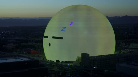 Illuminated-MSG-Sphere-With-Emoji-Face-On-Surface-Looking-Around