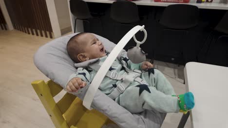 Adorable-4-month-old-bubbling-with-joy-in-a-baby-chair,-gleefully-jiggling-and-smiling