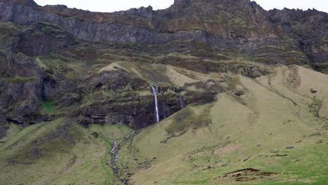 Grüner-Berghang-Mit-Einem-Wasserfall-In-Island,-Der-Die-Ruhe-Der-Natur-Zeigt