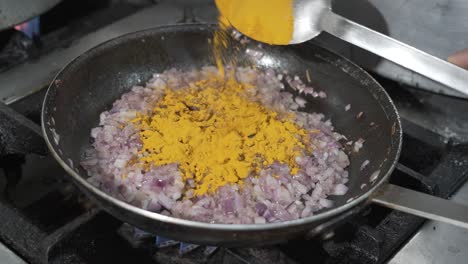 Adding-Turmeric-to-Sautéed-Onions-in-Pan