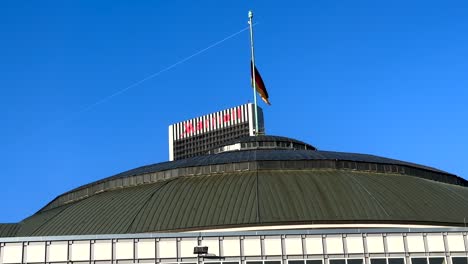 Wehende-Deutsche-Flagge-Auf-Dem-Dach-Eines-Gebäudes-Mit-Dem-Marriott-Hotel-Im-Hintergrund