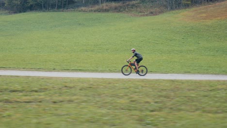 Ein-Männlicher-Fahrradfahrer-Rollt-Sanft-In-Der-Ferne-Mit-Seinem-Rennrad-In-Der-Natur