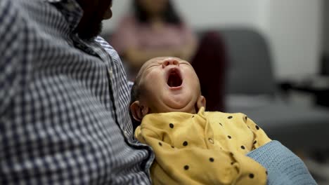 New-born-Indian-Baby-Boy-Yawning-In-Fathers-Arm-As-He-Rests