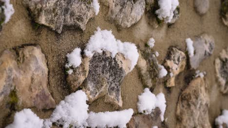 Detailed-shot-of-snow-falling-and-sitting-on-a-rock-wall-in-Guardiagrele,-Abruzzo,-Italy