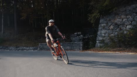 Männlicher-Fahrradfahrer,-Der-Mit-Seinem-Rennrad-In-Voller-Reitkleidung-Und-Helm-Eine-Bergstraße-Hinunterfährt