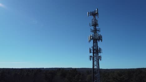 4K-aerial-slow-drone-approach-towards-a-cell-phone-tower-against-blue-sky