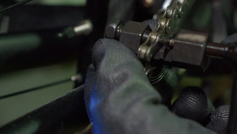 Mechanic-uses-chain-break-tool-to-remove-link-from-bike-chain,-closeup