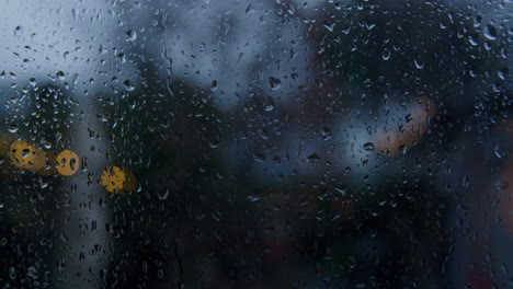 Slow-motion-of-raindrops-trickling-down-a-window-with-out-of-focus-lights-in-the-background