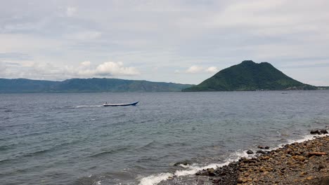 Scenic-ocean-view-on-Alor-Island-in-Alor-Archipelago,-eastern-Lesser-Sunda-Islands,-with-small-fishing-boat-and-volcanic-tropical-island-in-East-Nusa-Tenggara
