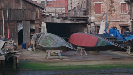 Artisan-repairing-a-gondola-at-Squero-di-San-Trovaso,-Venice-Italy