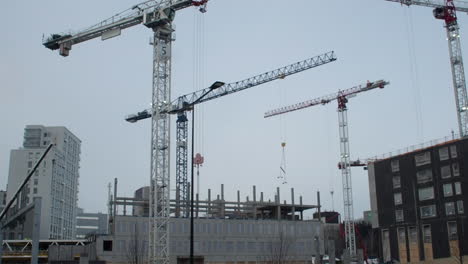 Urban-commercial-construction:-Tower-cranes-operate-in-the-grey-sky