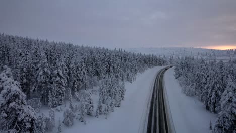 Vista-Aérea-Por-Drones-De-Un-Automóvil-En-Una-Carretera-Rodeada-De-Un-Bosque-Invernal-En-Laponia,-Finlandia,-Círculo-ártico